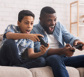 Father and son sitting on couch playing video games