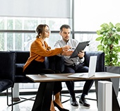 Man and woman sitting in office looking at tablet