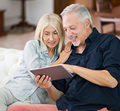Man and woman sitting on couch together and using digital tools on their tablet
