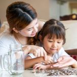 Mother and young daughter sitting at table counting change