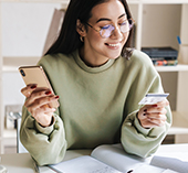 woman holding her credit card and phone