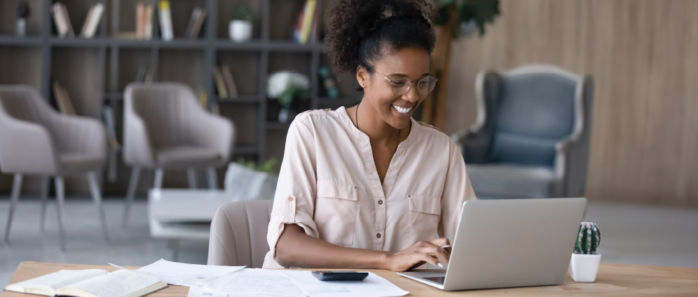 Woman in her 30’s sitting at laptop planning for early retirement.