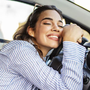 Woman leaning on steering wheel while smiling