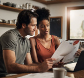 Couple sitting in kitchen together going through their finances.