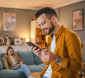 Man smiling holding a credit card and looking at his phone