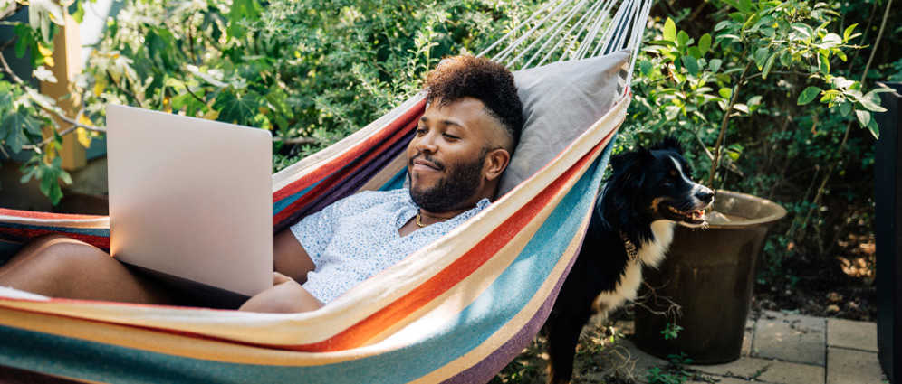 A man lying in a hammock with a laptop.