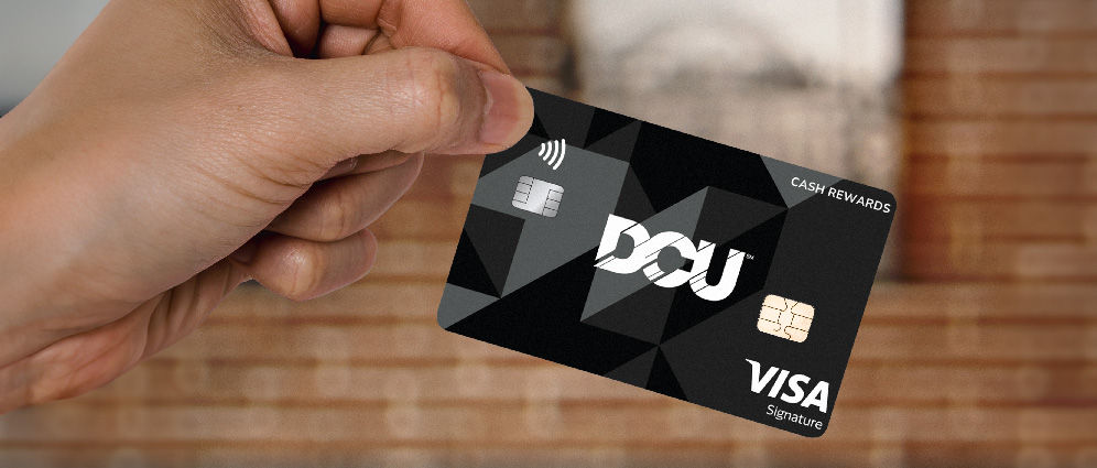 A hand holding a DCU Signature Visa Credit Card